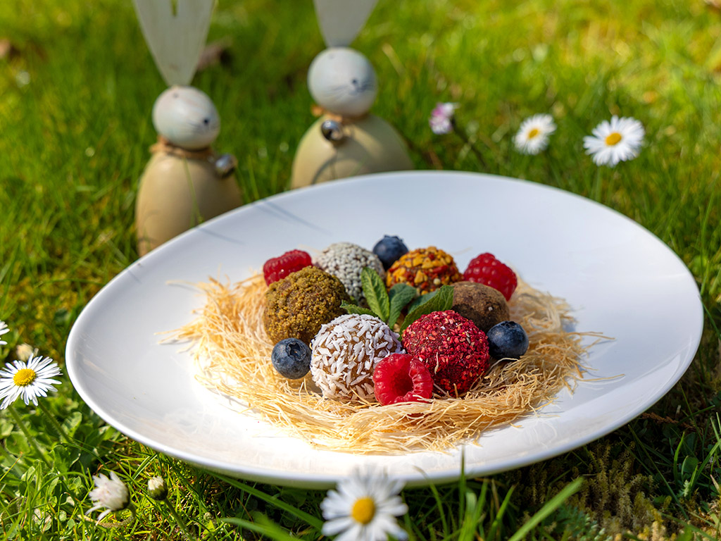 Bunte Energyballs schön angerichtet auf Frühlingswiese im Ayurveda Parkschlösschen mit Osterdeko