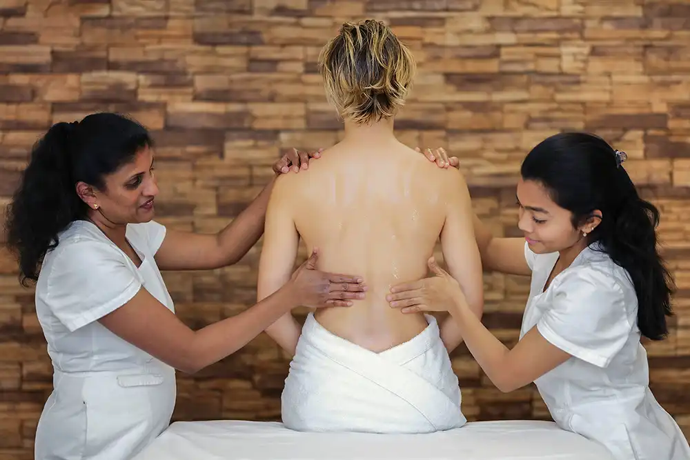 Person erhält traditionelle Synchronmassage während einer Panchakarma-Kur im Ayurveda-Hotel